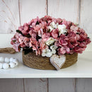 CESTO REDONDO M EM PALHA COM HORTÊNSIAS ENVELHECIDAS ROSADAS E CORAÇÃO 16AX32L/CM