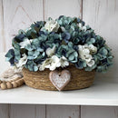 CESTO REDONDO M EM PALHA COM HORTÊNSIAS AZUIS ENVELHECIDAS E CORAÇÃO DE MADEIRA 16AX32L/CM