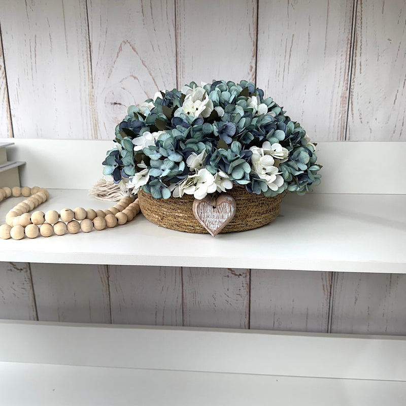 CESTO REDONDO M EM PALHA COM HORTÊNSIAS AZUIS ENVELHECIDAS E CORAÇÃO DE MADEIRA 16AX32L/CM